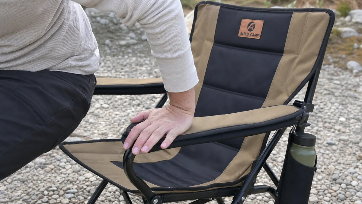 Close-up of a hand pressing down on the armrest of the ALPHA CAMP oversized camping chair while standing up from it