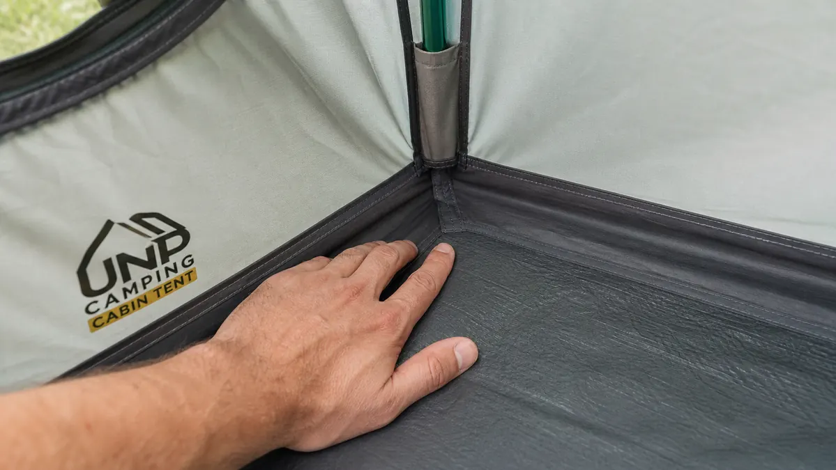 Hand pressing down a wrinkled section of tent floor near a corner seam looking for a missed seam-tape spot
